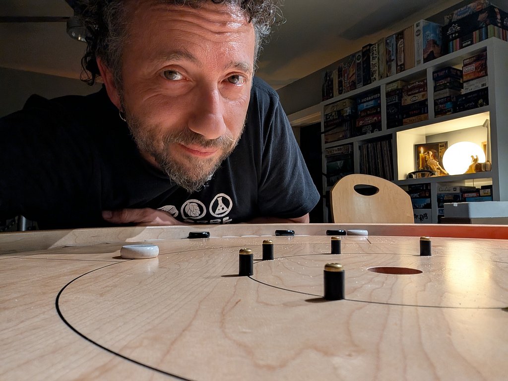 Dave Kaminsky leaning over a crokinole board